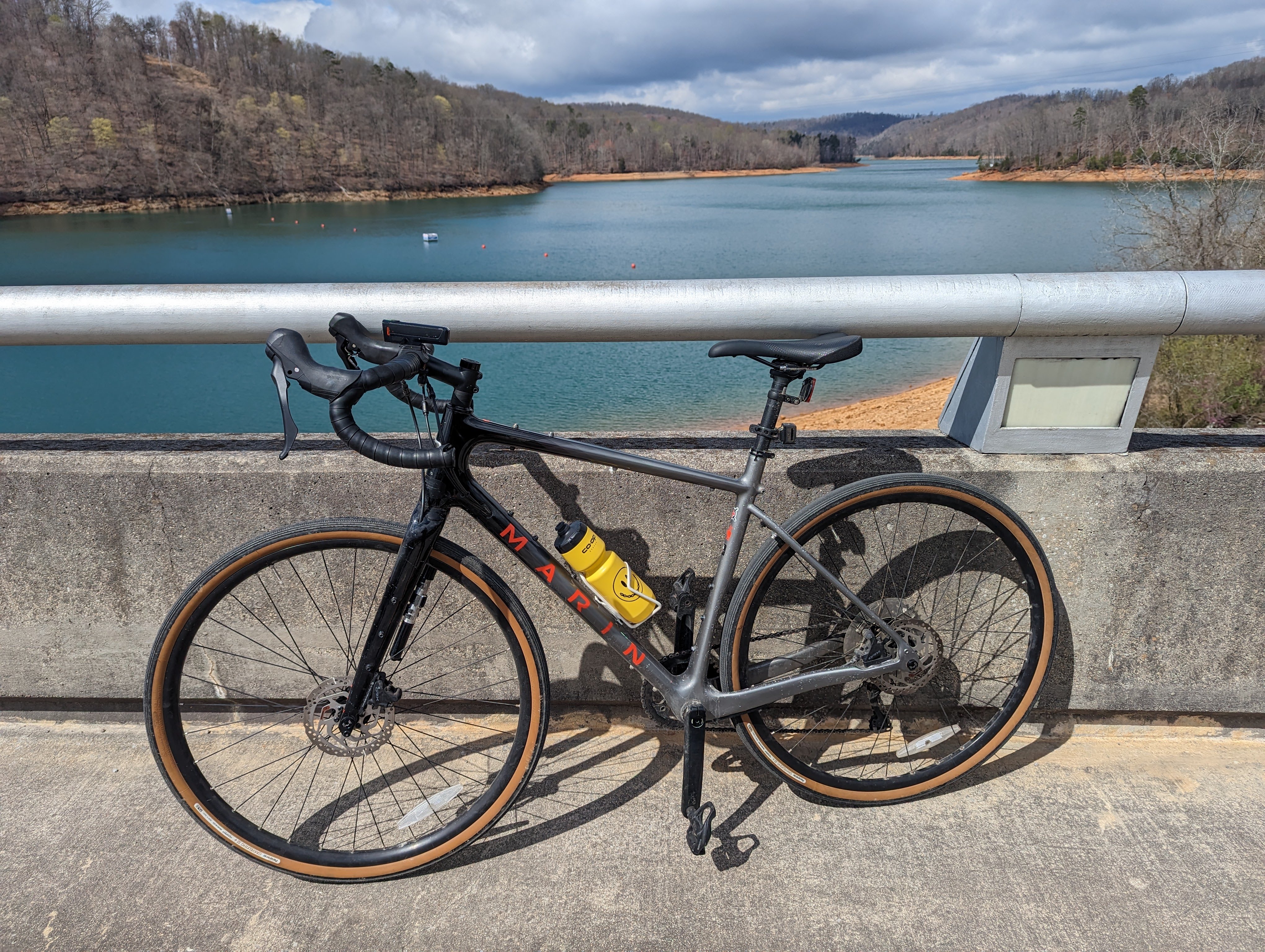 gray and black gravel bike leaning against a concrete guard rail overlooking Norris Lake in winter